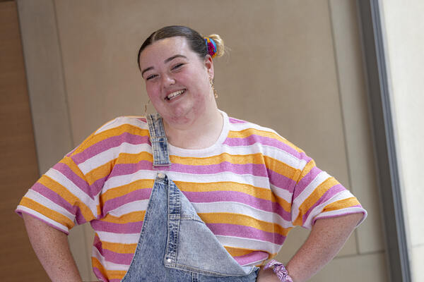Abbey, a young Australian who has benefited from Canteen's free cancer help, smiling at the camera wearing dungarees