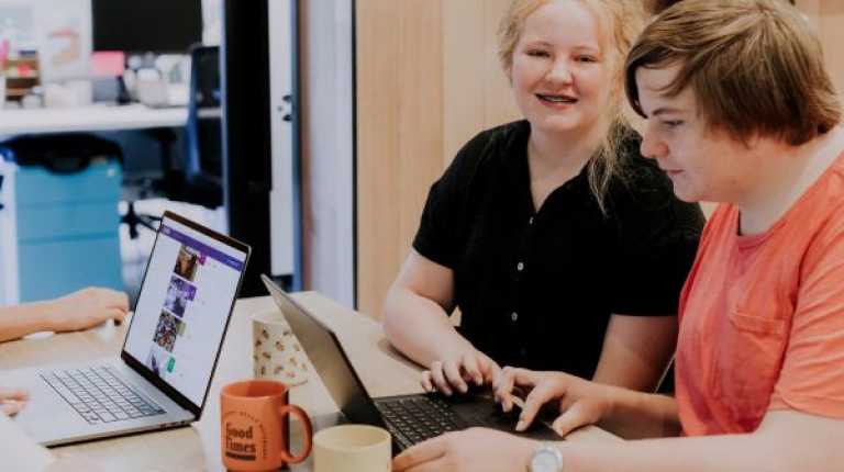 A young girl and young boy working on laptops at a table 