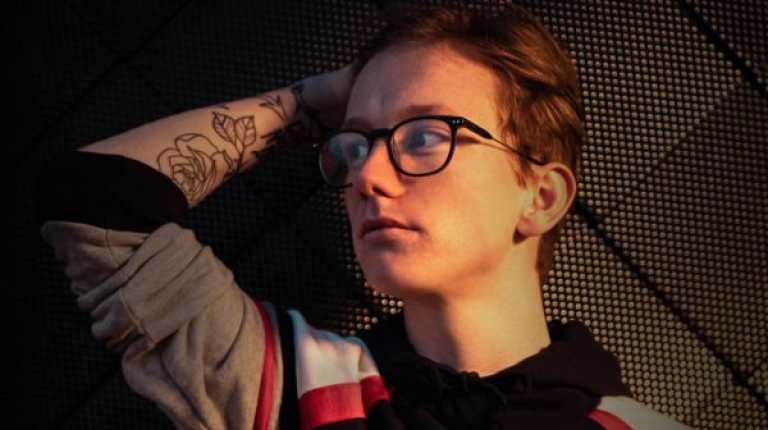 Young person lying on their bed looking moodily to the side
