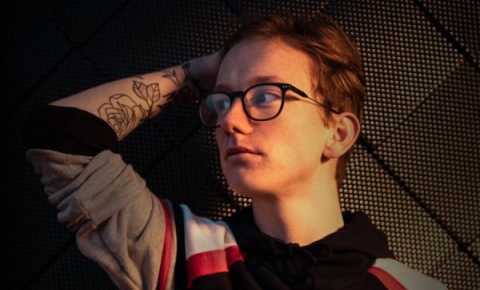 Young person lying on their bed looking moodily to the side