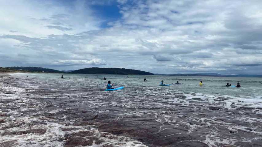 young people trying surfing at dodges ferry in tasmania with canteen