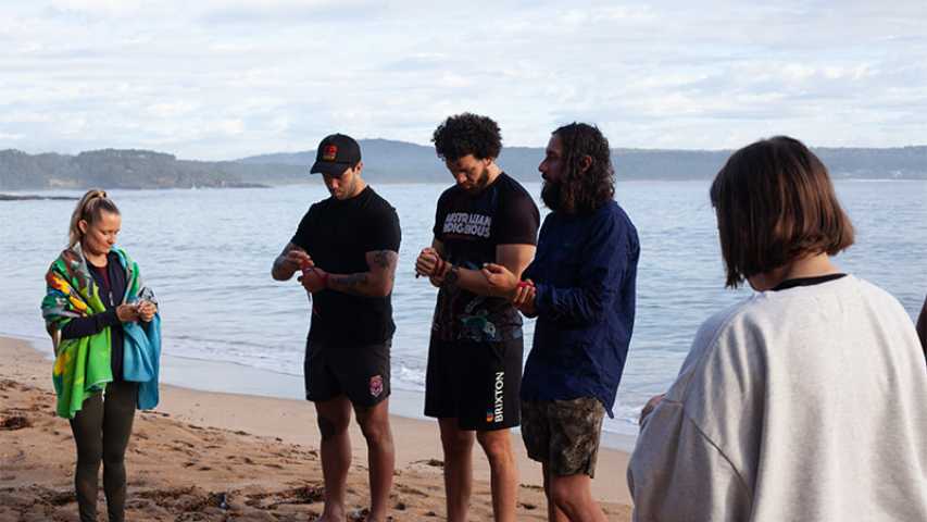five young people on the beach putting on wrist bands at the canteen first nations cultural program
