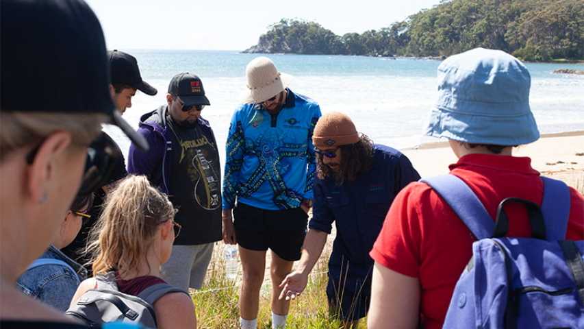 a guide taking a group of young people on a tour at the beach during the canteen first nations cultural program