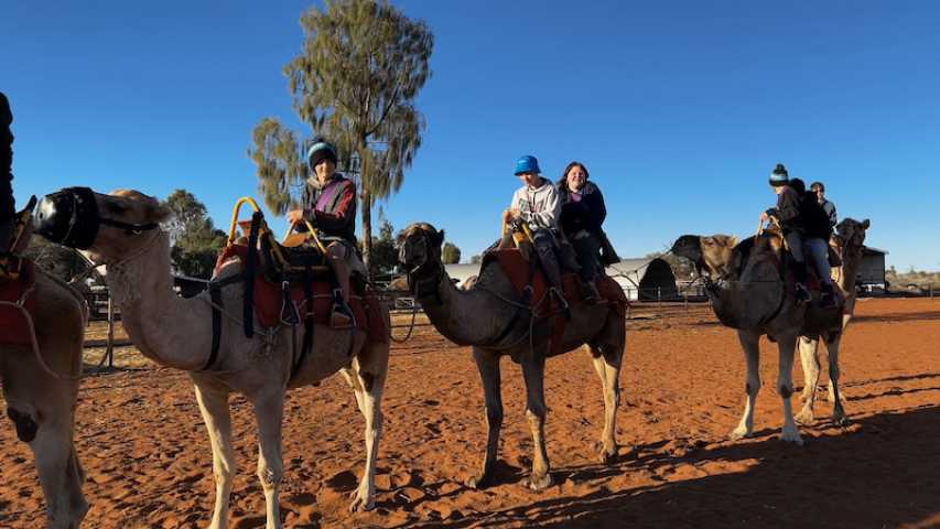 young people riding camels on Anangu Island