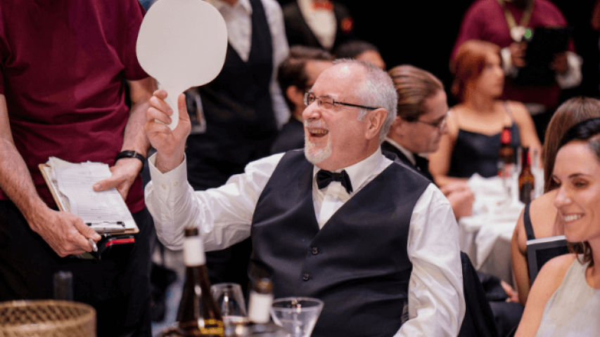 David Weston from Lagardere AWPL is holding up a paddle at the gala fundraiser event