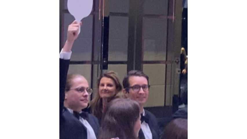 Alex Graham from MoneyMe is is holding up a paddle at the gala fundraiser event