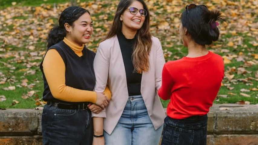 three young people laughing and having a conversation 