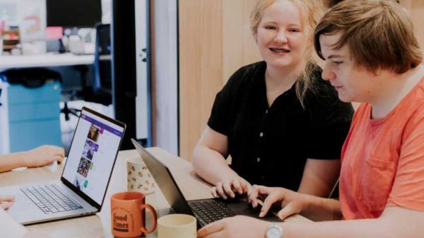 A young girl and young boy working on laptops at a table 